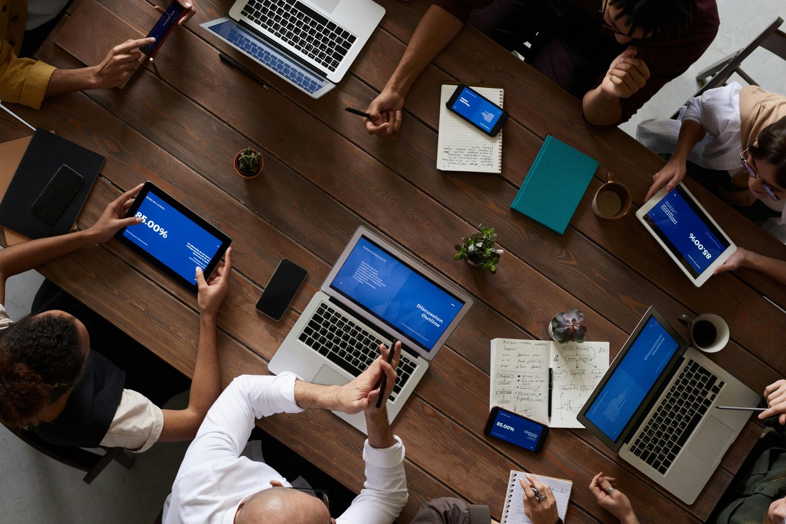 Home Overhead view of a diverse team discussing around a wooden table, using technology.